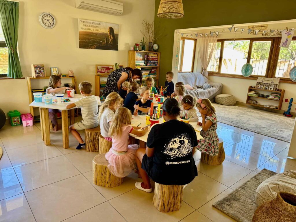 Kinder die um einen Tisch sitzen bei dem deutschen Kindergarten in Windhoek - Die Löwenkinder